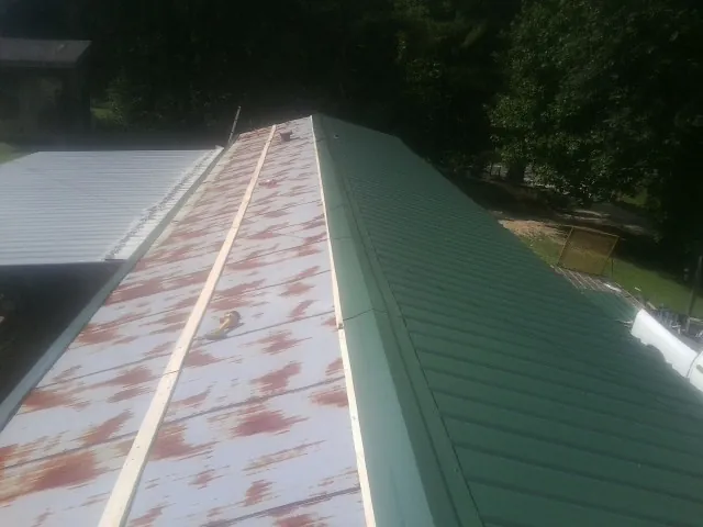 Old rusted panels beside newly installed green metal roofing — Wind Damage Roof Repair by Roofing Brothers in Berkey