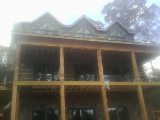 Dormers and porch framing on a large log home under construction — Roof Coating work by our crew in Berkey