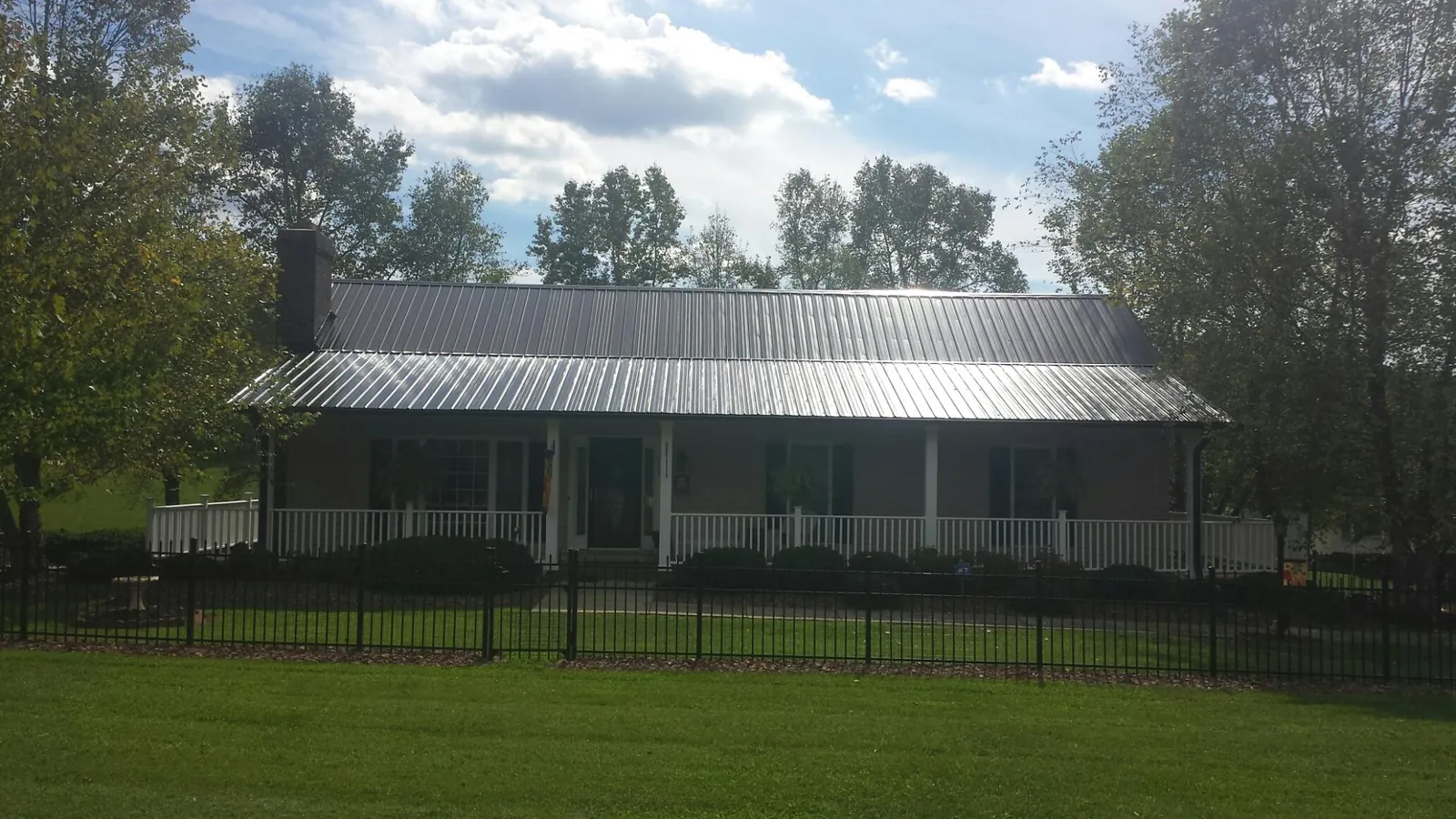 Gray metal roof on a brick ranch with a full width front porch — Gutter Guard Installation work by our crew in Berkey