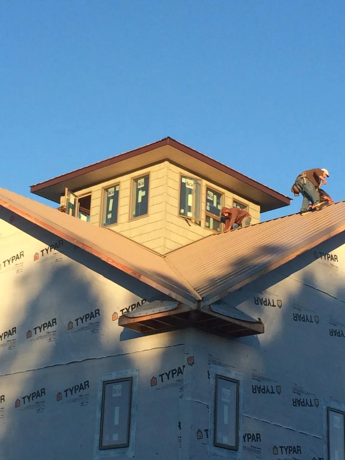 Roofers working around a rooftop cupola on a new metal roof at sunset — Roof Waterproofing in Berkey by Roofing Brothers